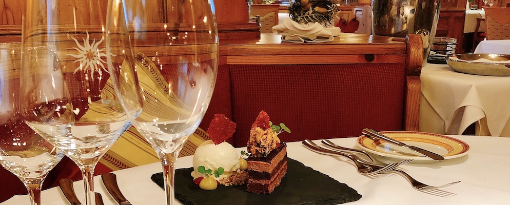 Blick ins Restaurant Sonne. Foto zeigt ein Dessert, umrahmt von Weingläsern und edlem Besteck.
