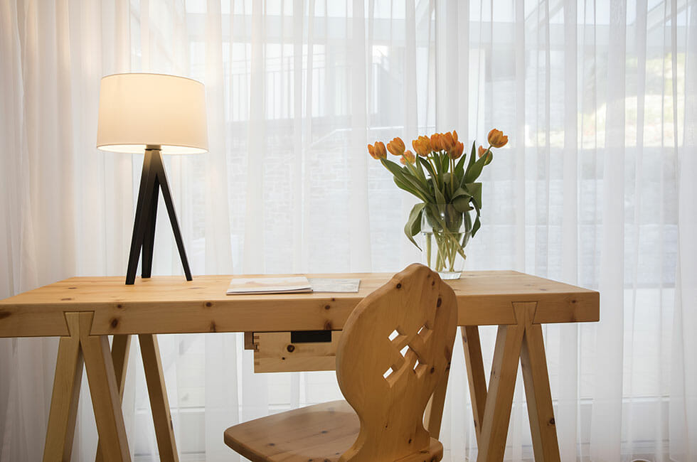 Zirbenholz Doppelzimmer, Schreibtisch mit Sitzgelegenheit und großer Fensterfront.
